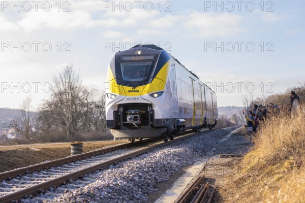 Modern train travels on tracks through rural winter landscape under clear skies, fire brigade