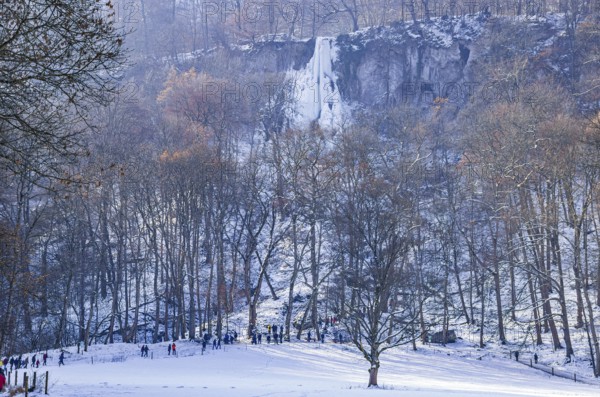 Numerous day trippers hike to the Urach waterfall full of bizarre ice formations, frozen at low
