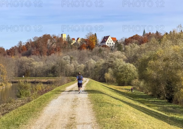 Jogger on a path along the Isar with a view of Grünwald with Bürg Grünwald, Grünwald, Bavaria,