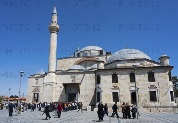 Visitors enter a historic mosque with several domes and minarets, prayer in front of the mosque,