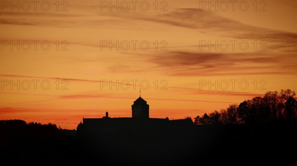 Silhouette of a castle at sunset, warm tones above the horizon, view of Rosenberg Fortress,