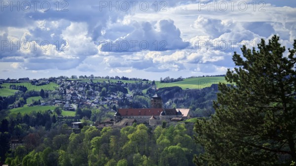 View of a castle surrounded by green hills and dramatic clouds, view of Rosenberg Fortress,
