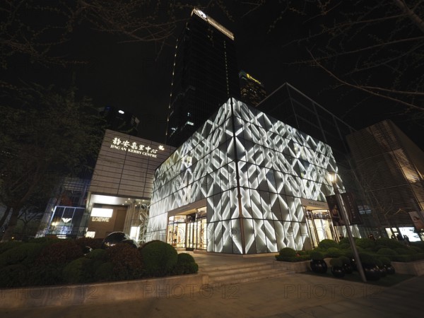 Modern building, Jing An Kerry Centre, at night with illuminated façade in an urban setting,