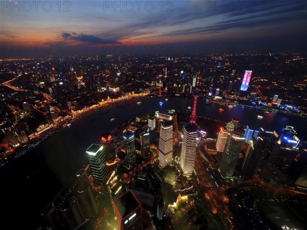 Illuminated city at dusk with view of river and skyscrapers, Shanghai, China