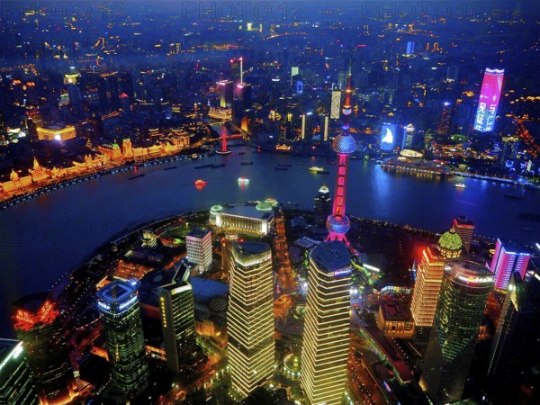 Glowing city view at night with illuminated skyscrapers along a river, Shanghai, China