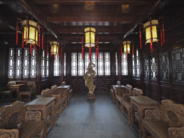 An elegant interior design with Asian lanterns, wood decor, and ornate furniture in warm tones,