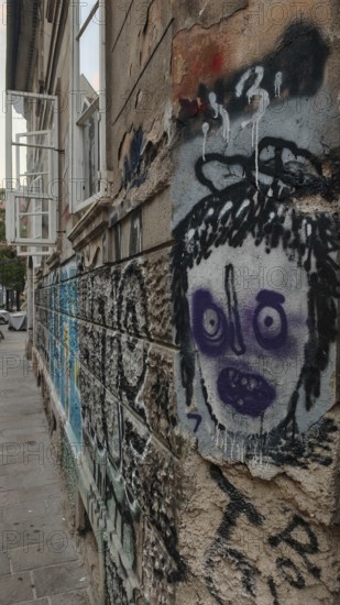 Street scene with graffiti and sprayed face on a weathered wall in an urban environment, Ljubljana,