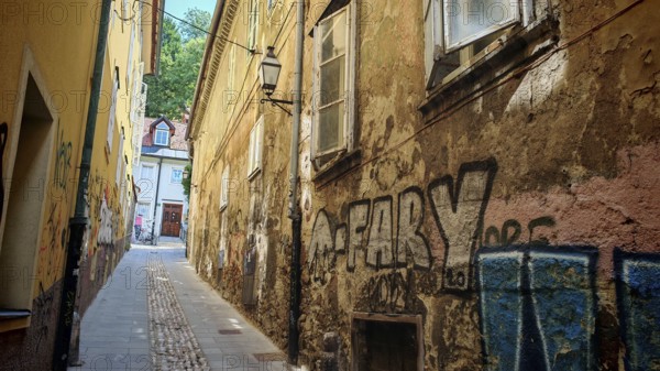 Narrow alleys with graffiti, historic facades and colorful tones dominate the picture, Ljubljana,