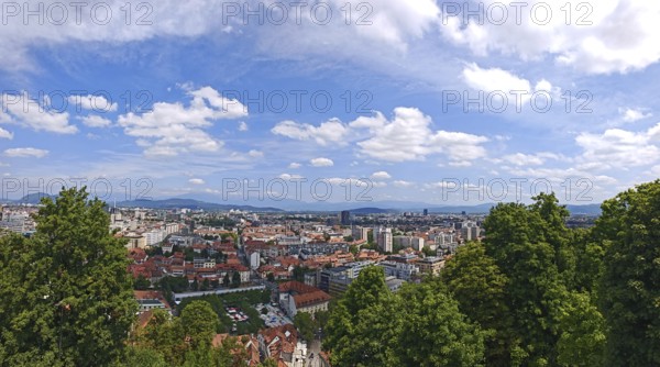 Panoramic view of an urban landscape under blue sky with mountains in the background, Ljubljana,