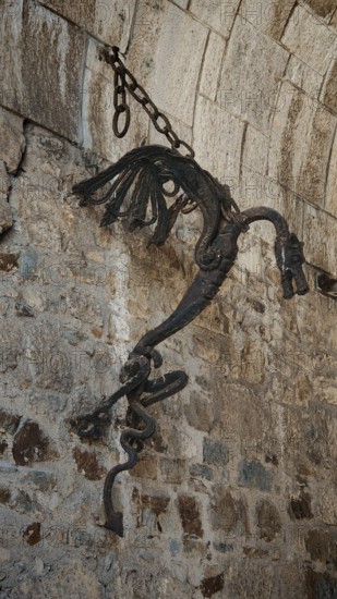 Ancient metal sculpture, Ljubljana dragon hanging on a stone wall surrounded by historic