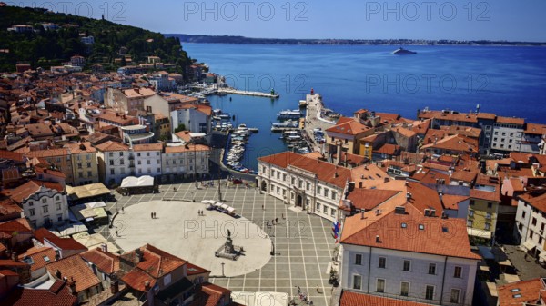 Aerial view of a coastal town with red roofs, a harbor and a main square on the blue sea, Piran,