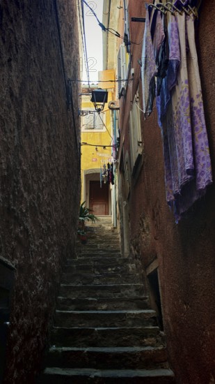 A narrow stone staircase in an old alley with suspended laundry and shade, Piran, Slovenia