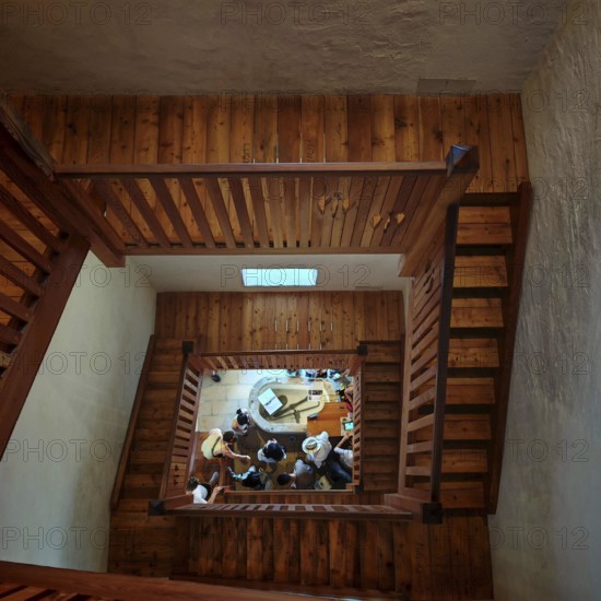 Wooden staircase looking down at a group of people gathered on the ground floor, Piran, Slovenia