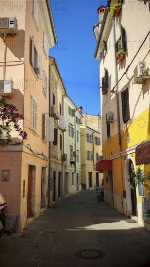 A narrow, colorful alley in a Mediterranean town in bright sunshine, Piran, Slovenia