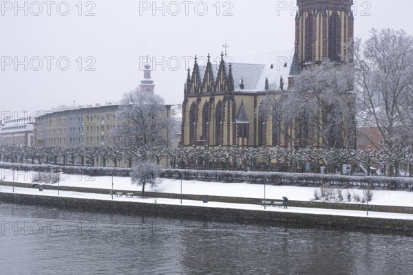 A passerby walks along the banks of the Main with an umbrella. Heavy snowfalls have caused another