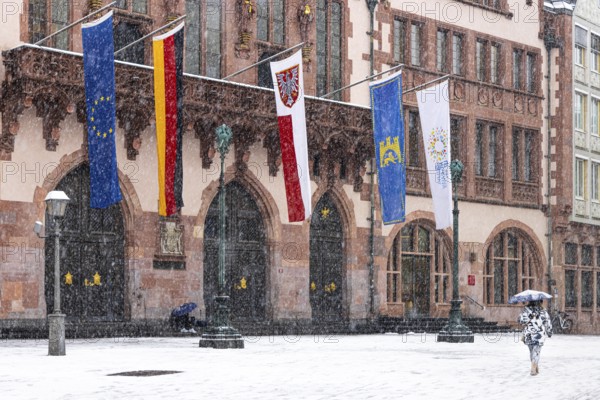 A passer-by walks across Frankfurt's Römerberg with an umbrella. Heavy snowfalls have caused