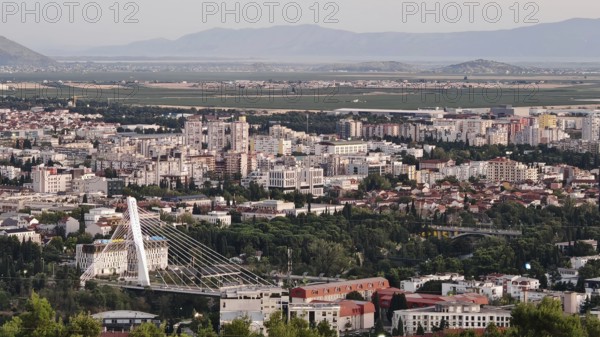 A city surrounded by nature with trees in the foreground and mountains in the background,