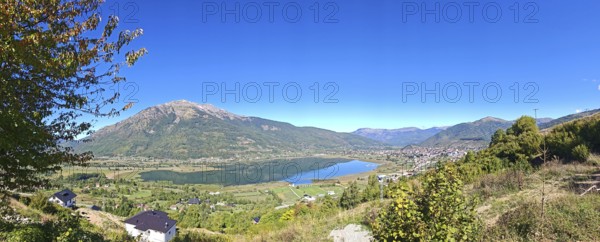 Wide view over a lake and mountains under a clear blue sky, view from above over Lake Plav,