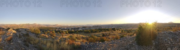 A city surrounded by nature with trees in the foreground and mountains in the background,
