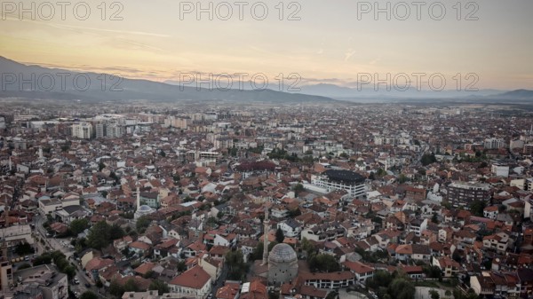 Extensive view of the city in evening light with mosque and mountains on the horizon, Prizren,