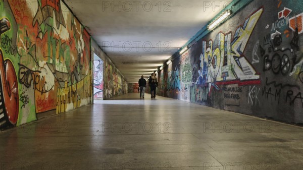 Long tunnel with colorful graffiti on the walls, some people can be seen in the background, Prague,