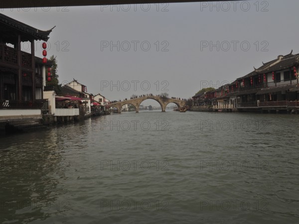 Traditional Chinese architecture on a quiet river with bridge under cloudy sky, Zhujiajiao Ancient