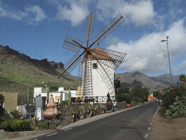 Traditional windmill along a road against a mountainous backdrop, Mogan windmill, Gran Canaria,