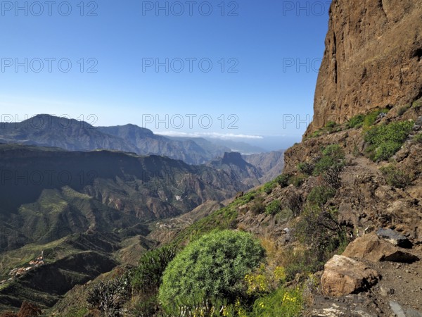 View of a deep valley and distant mountains from a mountain trail, Roque Bentayga, Gran Canaria,