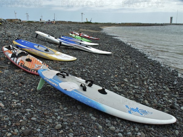 Pebble beach with colorful surfboards at sea under cloudy sky, Pozo Izquierdo, Gran Canaria, Canary