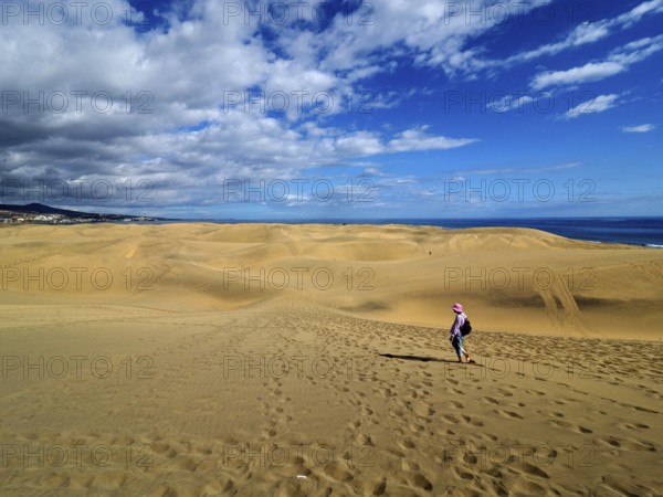 Wide sand dune landscape with a hiker under the blue sky, dunes of Maspalomas, Gran Canaria, Canary