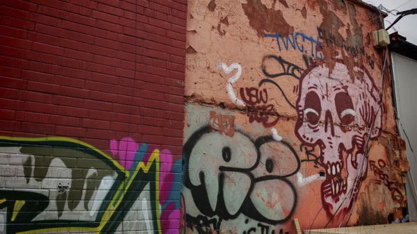 Colourful graffiti on an old wall with a skull motif and various lettering in an urban environment,
