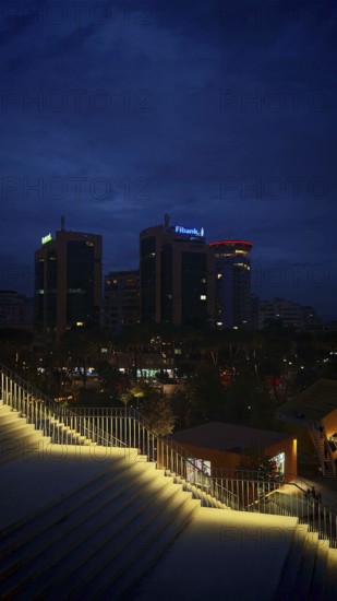 Nighttime city view with illuminated buildings and illuminated staircases in the foreground,