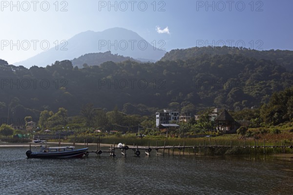 Colourful boats in the port of San Juan la Laguna, behind the Dan Pedro volcano in the haze,