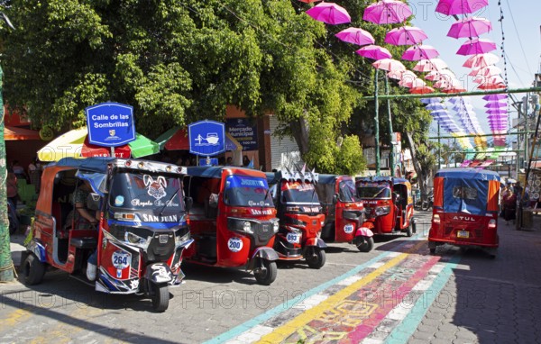 Red tuk tuks or tricycle taxis in an alley in San Juan la Laguna, Atitlán, Sololá Department,