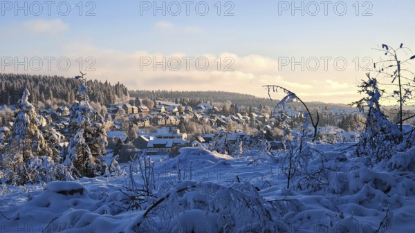 Winter village in snowy landscape with hills and forests in the evening light, Rennsteig,