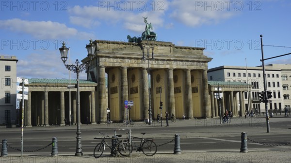 Famous gate in Berlin, Brandenburg Gate with a few bicycles in the foreground and blue sky,