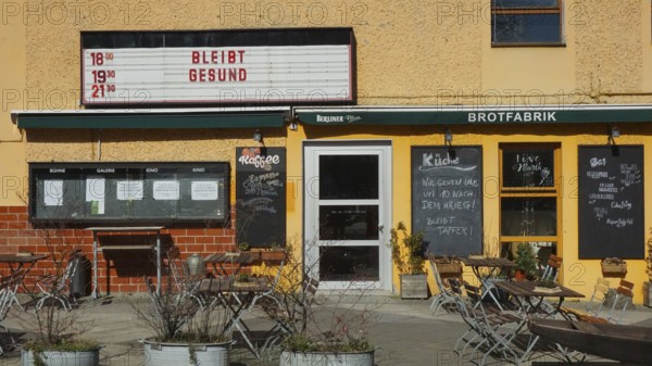 Small café with outdoor seating area and menu boards when the sun is shining with stays healthy and