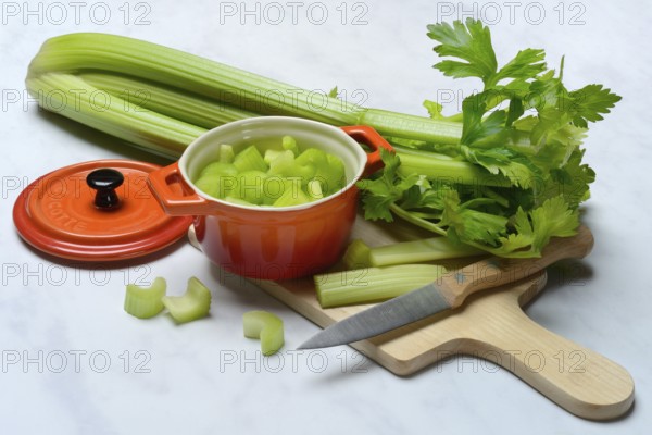Celery stalks, pieces in pots with kitchen knife