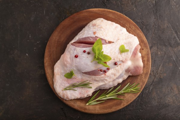 Raw Turkey Thigh with spices and rosemary on cutting board on black concrete background. top view,