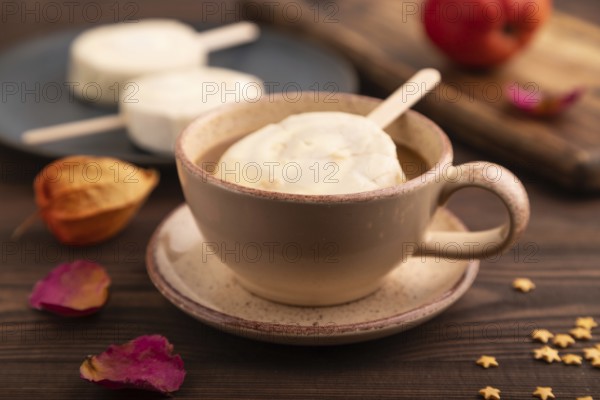 ?hocolate Ice cream in white glaze, cup of coffee, on brown wooden background, side view, close up,
