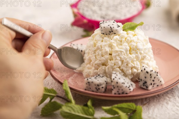 White ?ottage cheese, Curd, with Pithaya with hand on gray concrete background and linen textile,