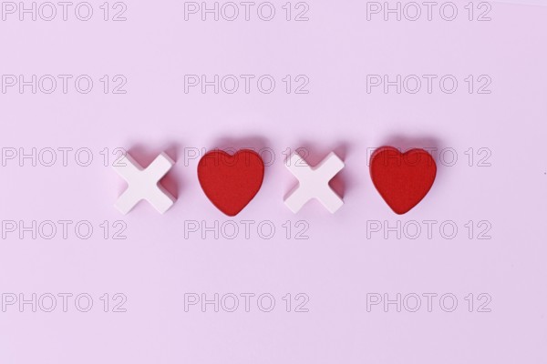 Valentine flat lay with wooden light pink and red hearts forming XOXO letters arranged on a pink