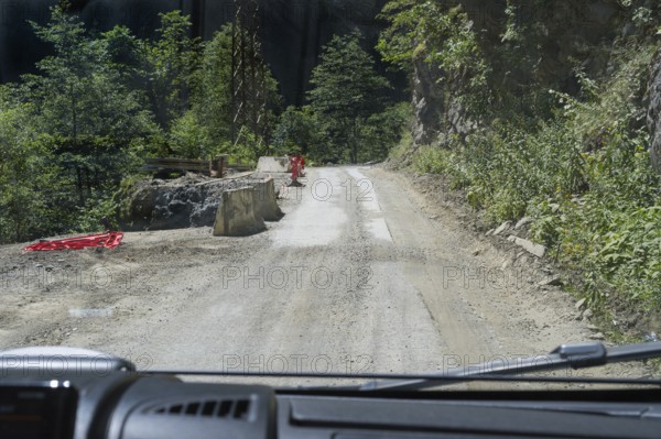 Narrow dirt road leads through wooded mountains, road 7 partly slipped down, west of Mestia,