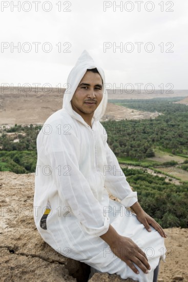 Young man and oasis in the background, near Merzouga, Meknès-Tafilalet region, Erg Chebbi, northern