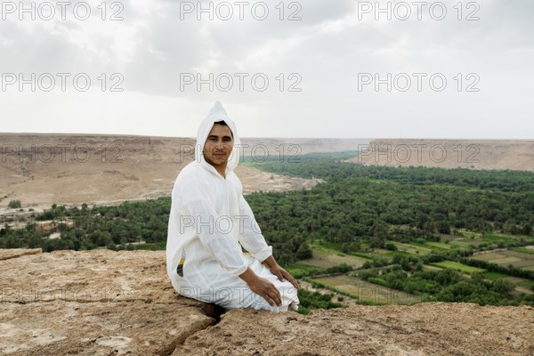 Young man and oasis in the background, near Merzouga, Meknès-Tafilalet region, Erg Chebbi, northern