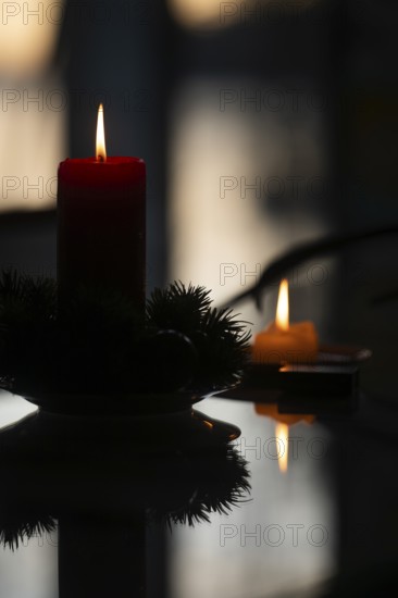 Two candles stand on a table in front of a window at dusk and create a Christmas atmosphere,