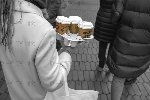 Lady carrying three coffees to go on the street, black and white, Nuremberg, Middle Franconia,