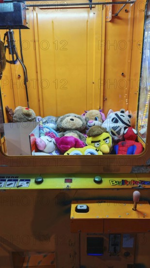 Automatic grappling machine full of colorful stuffed animals in a yellow case, Batumi, Georgia