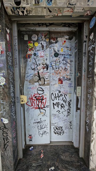 Elevator doors covered with graffiti and stickers in an urban setting, Prizren, Kosovo
