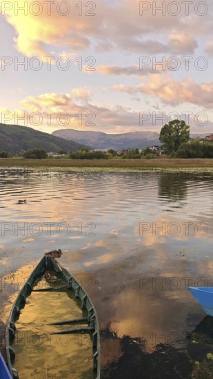 A lonely boat on a picturesque lake at sunset with mountain views, Plav Lake, Montenegro